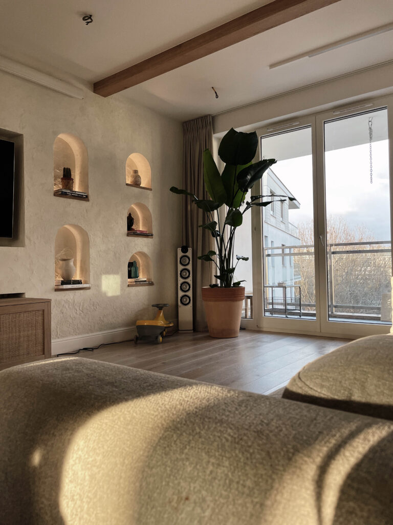 Jasny salon z wysoką rośliną przy oknie tarasowym