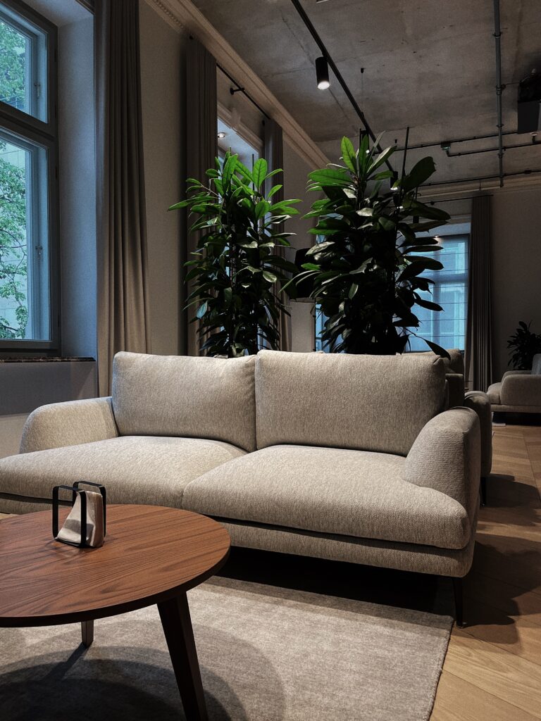 Sofa w biurze, za nią duże rośliny w donicach