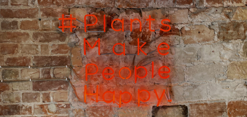Neon „Plants make people happy” na ceglanej ścianie